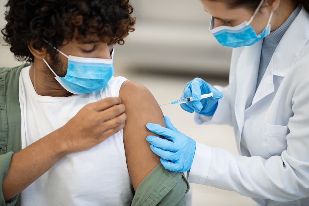 Brown skinned man with curly hair gets vaccination shot